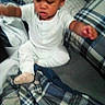 Fasha Douglas is registered to the contest to win money with this photo: baby, blanket, casual, child, clothing, couch, expression, face, footwear, furniture, home, indoor, motion, pajamas, person, plaid_blanket, sitting, soft_fabric, toddler, young_child