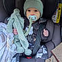 baby, car_seat, pacifier, knit_hat, plush_toy, blanket, clothing, seat_belt, infant, child, cute, indoors, portrait, comfort, warm, soft_toy, expression, sitting, car_interior, young_child