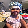baby, child, smiling, dress, bonnet, indoor, bed, blanket, toy, furniture, person, face, cute, happy, infant, portrait, skin, headwear, room, sitting