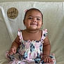 Kalani joined the competition — help win amazing prizes! baby, child, smiling, dress, pink, blue, floral_pattern, sitting, blanket, indoor, portrait, cute, happy, earrings, hair_bow, milestone, sign, wooden_sign, infant, toddler