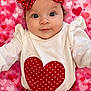 baby, infant, child, red_bow, polka_dot, heart_pattern, pink_background, white_shirt, cute, portrait, smiling, headband, clothing, fabric, sitting, face, eyes, adorable, closeup, baby_girl