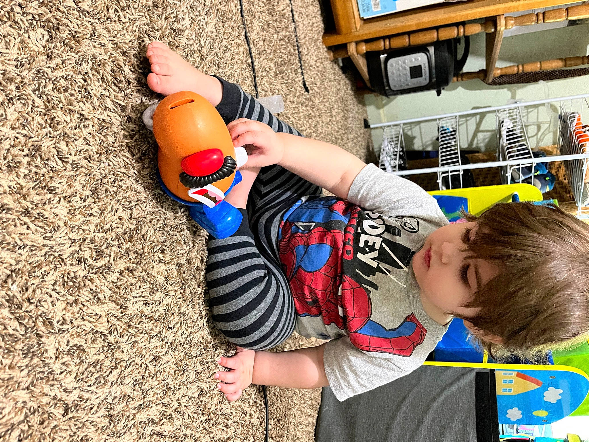 Caden is registered to the contest to win money with this photo: bookcase, child, electric_blue, finger, fun, gesture, hand, happy, human, human_leg, nail, person, picture_frame, play, shelf, shelving, t_shirt, television, thumb, toddler