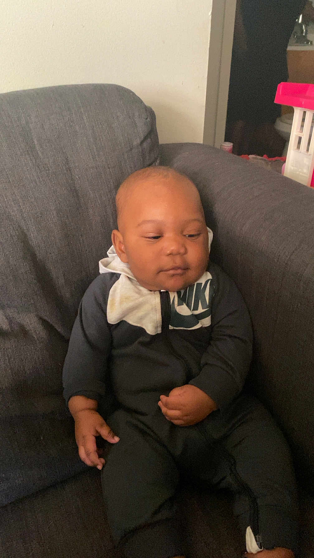 Jahari is registered to the contest to win money with this photo: baby, infant, child, person, couch, sofa, clothing, nike, black_outfit, indoor, seated, furniture, young_child, portrait, one_person, casual, relaxed, home, cozy, face