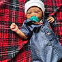 Jahari is registered to the contest to win money with this photo: baby, infant, pacifier, hat, clothing, onesie, plaid_blanket, red, black, blue, face, hand, lying_down, cute, newborn, child, portrait, indoors, cozy, soft