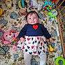 Aluney participe au concours pour gagner de l'argent avec cette photo : baby, crib, toy, plush_toy, rattle, quilt, floral_pattern, heart_pattern, infant, child, clothing, wooden_crib, colorful, cute, lying_down, smiling, playtime, indoor, person, portrait