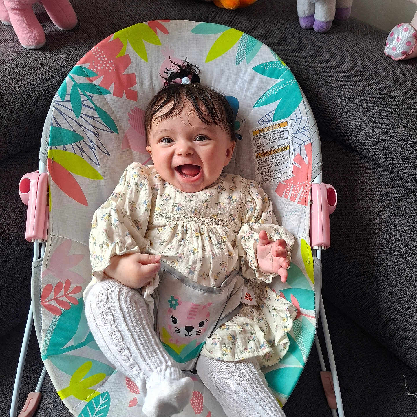 Aluney a rejoint le concours — aidez-le/la à gagner de superbes lots ! baby, smiling, baby_rocker, floral_dress, white_tights, plush_toys, pink_unicorn, chicken_toy, gray_couch, happy, sitting, indoor, child, cute, person, playful, infant, colorful, hair_ponytail, baby_clothing
