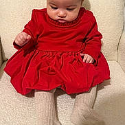 Nayla participe au concours pour gagner de l'argent avec cette photo : baby, child, red_dress, tights, sitting, chair, indoors, cute, infant, portrait, soft_texture, cozy, looking_down, long_sleeves, toddler, small_hands, footwear, plush, comfortable, young_child