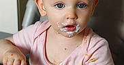 Elizabeth participe au concours pour gagner de l'argent avec cette photo : baby, child, closeup, curious_eyes, eating, face, food, hand, high_chair, indoor, mealtime, mess, milk_mustache, pink_shirt, portrait, spoon, stains, toddler, tray, yogurt