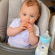 Elizabeth participe au concours pour gagner de l'argent avec cette photo : baby, high_chair, bottle, milk, snack, white_shirt, blue_eyes, face, hands, feeding, infant, child, cute, indoor, portrait, table, food, mealtime, happy, toddler