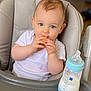 baby, high_chair, bottle, milk, snack, white_shirt, blue_eyes, face, hands, feeding, infant, child, cute, indoor, portrait, table, food, mealtime, happy, toddler