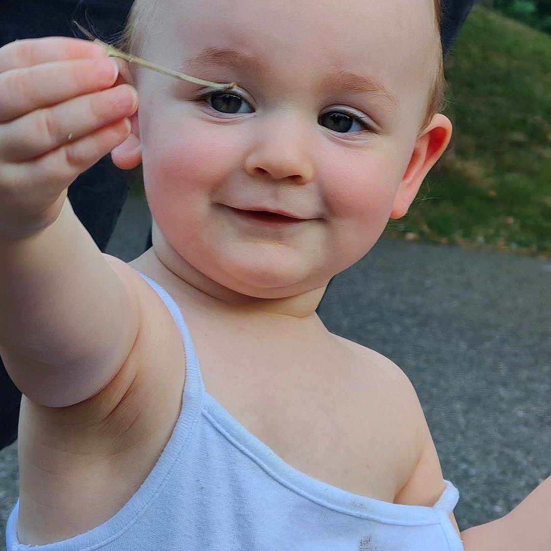Elizabeth participe au concours pour gagner de l'argent avec cette photo : arm, casual_clothing, child, curly_hair, cute, eyes, face, grass, hand, happy, nature, outdoor, pavement, person, playful, skin, smile, toddler, white_tank_top, young_child