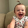 baby, child, smiling, happy, indoor, couch, clothing, person, face, foot, hand, hair, ponytail, pattern, hearts, infant, cute, joyful, sitting, skin