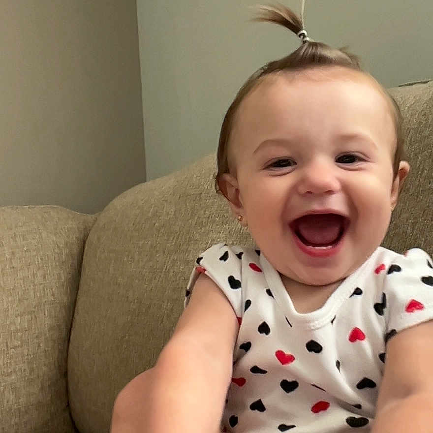 Madison joined the competition — help win amazing prizes! baby, child, smiling, happy, indoor, couch, clothing, person, face, foot, hand, hair, ponytail, pattern, hearts, infant, cute, joyful, sitting, skin