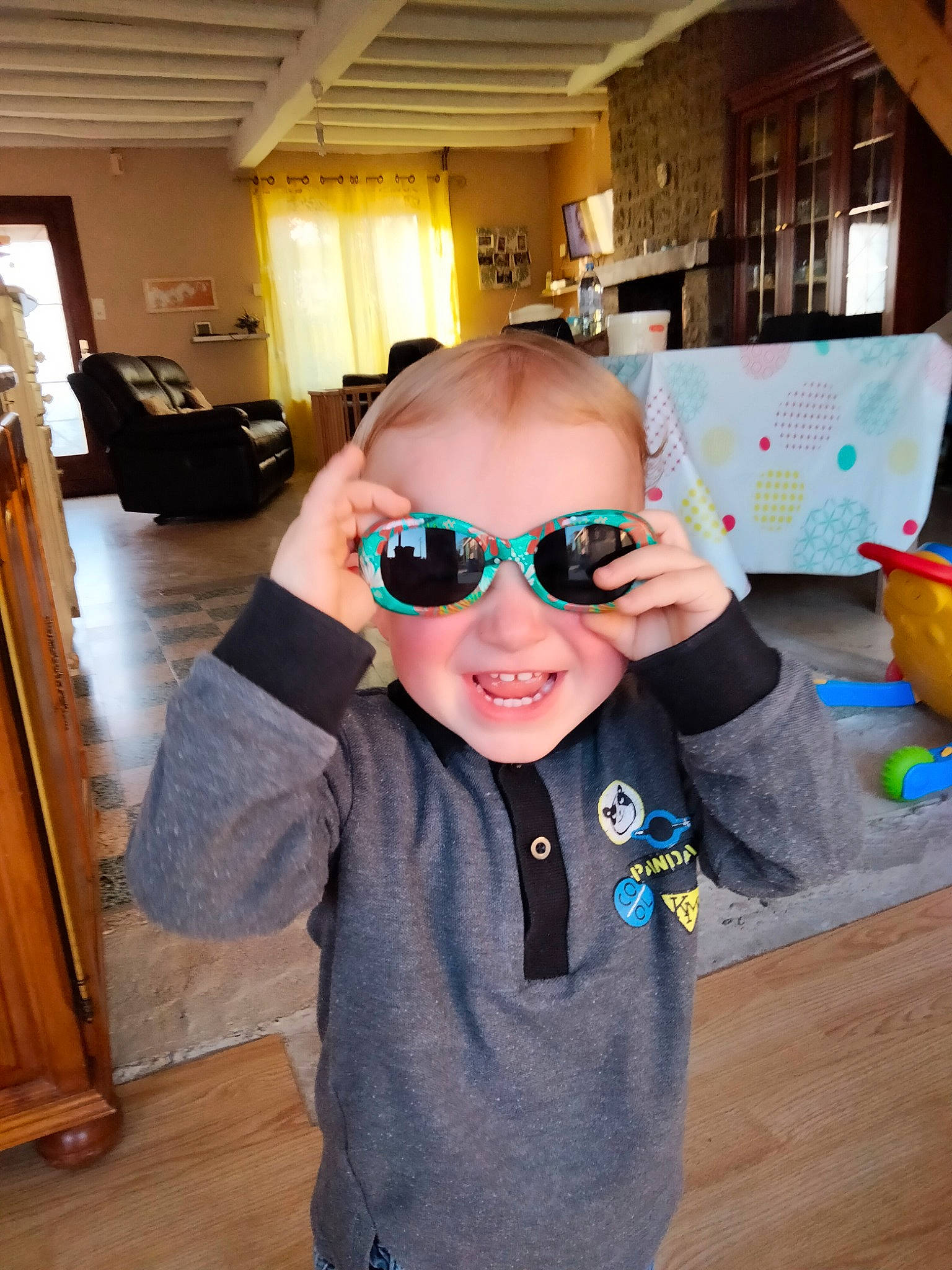 Melvin participe au concours pour gagner de l'argent avec cette photo : child, chin, eyewear, fashion_accessory, flooring, fun, glasses, goggles, happy, hardwood, headgear, joy, person, personal_protective_equipment, room, sleeve, smile, sunglasses, t_shirt, toddler