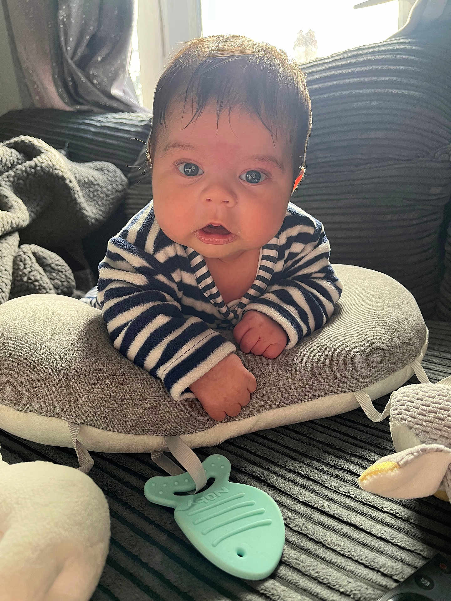 Zayne is registered to the contest to win money with this photo: baby, infant, striped_clothing, pillow, soft_toy, blanket, indoor, curious, face, hands, couch, child, young, cute, portrait, closeup, home, comfort, teething_toy, expression