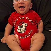 Austin joined the competition — help win amazing prizes! baby, infant, smiling, red_onesie, sitting, happy, face, barefoot, chubby_legs, cute, indoors, portrait, child, clothing, expression, skin, person, young, head, background