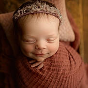 Paisley joined the competition — help win amazing prizes! baby, newborn, infant, sleeping, smiling, wrapped, blanket, headband, soft_texture, closeup, portrait, cozy, warm_lighting, peaceful, cute, child, indoor, face, hands, toddler