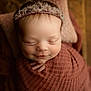 baby, newborn, infant, sleeping, smiling, wrapped, blanket, headband, soft_texture, closeup, portrait, cozy, warm_lighting, peaceful, cute, child, indoor, face, hands, toddler