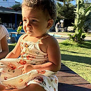Zahraa a rejoint le concours — aidez-le/la à gagner de superbes lots ! toddler, child, outdoor, sunlight, dress, floral, table, wood, greenery, tree, plant, grass, sky, curly_hair, earrings, person, portrait, summer, nature, daytime
