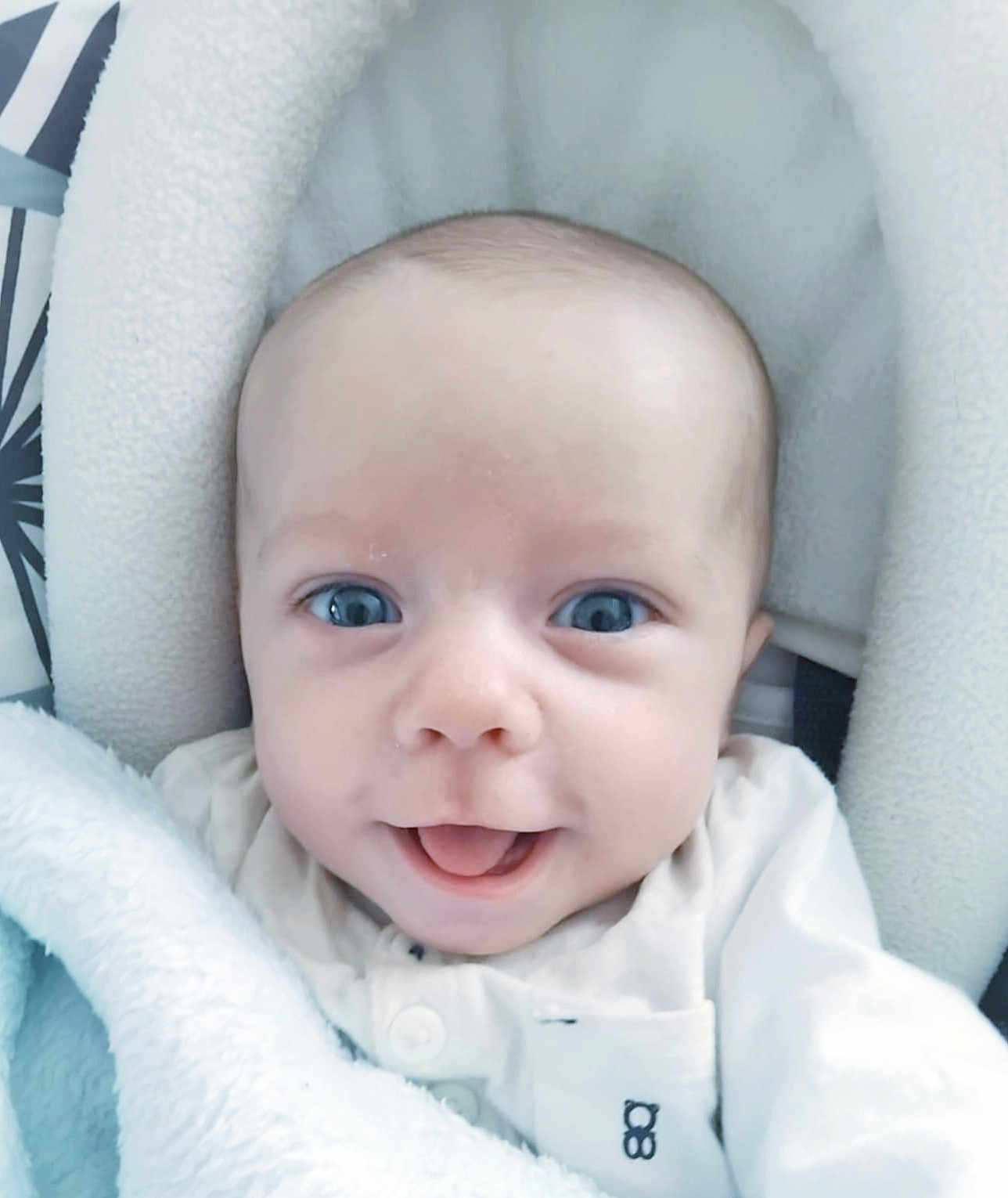 Eden a rejoint le concours — aidez-le/la à gagner de superbes lots ! baby, infant, face, tongue, blue_eyes, blanket, white_clothing, cushion, close_up, cute, smiling, child, newborn, soft_texture, indoor, portrait, person, cozy, head, seat