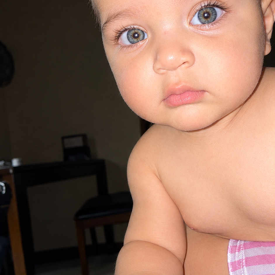 Eitham is registered to the contest to win money with this photo: baby, infant, child, portrait, close_up, face, eyes, wide_eyed, indoors, home, dining_area, table, chair, towel, pink_stripes, bare_shoulders, sitting, curious, flash_photography, photograph