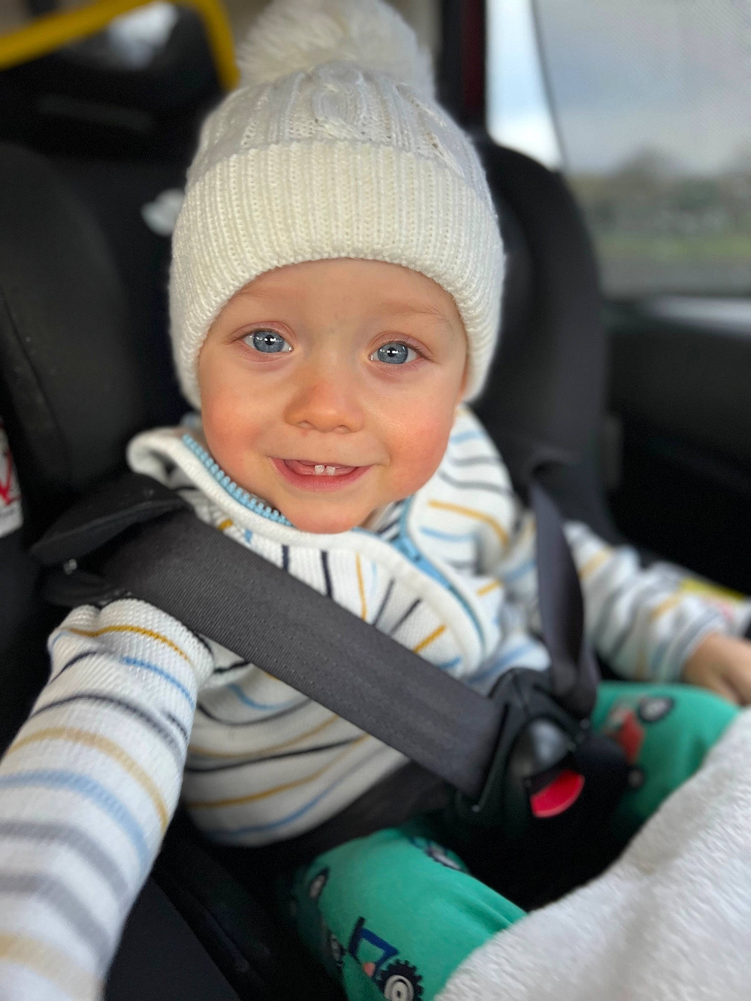 Devon is registered to the contest to win money with this photo: auto_part, automotive_design, baby, baby_carriage, baby_products, cap, car_seat, child, comfort, electric_blue, facial_expression, fashion_accessory, fun, happy, headwear, joy, knit_cap, luxury_vehicle, person, seat_belt