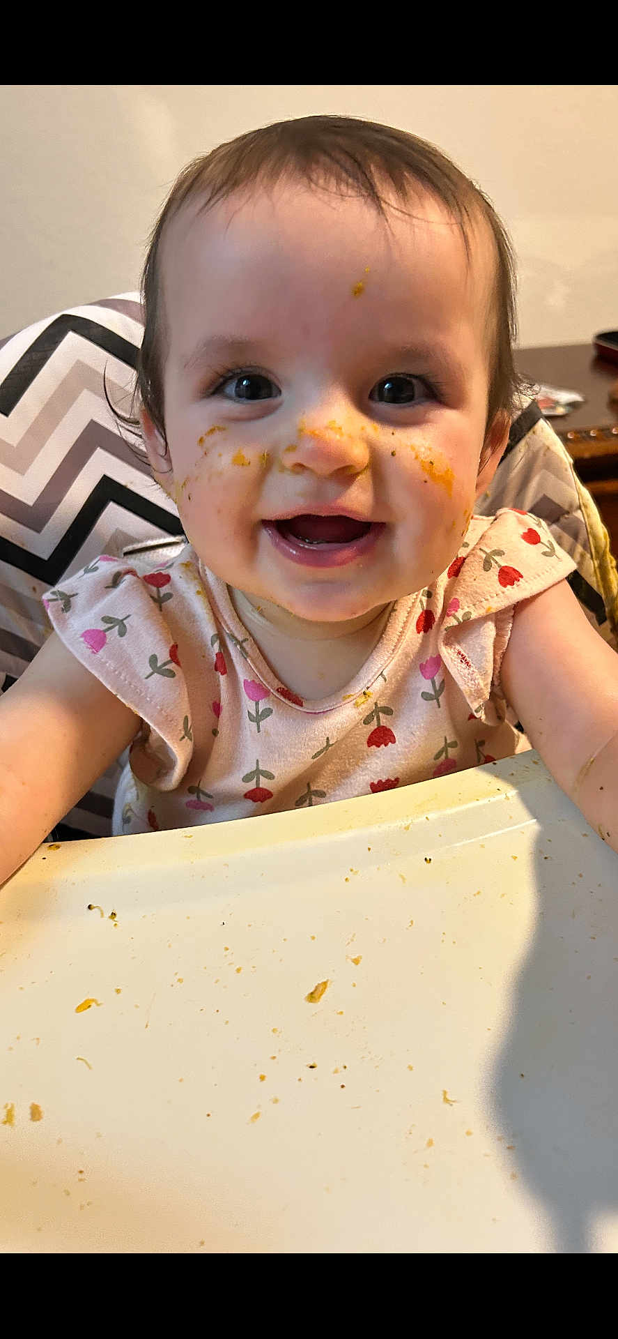Elizabeth joined the competition — help win amazing prizes! baby, child, high_chair, messy_face, food, smiling, happy, indoor, cute, clothing, table, feeding, face, person, toddler, meal, expression, cheerful, pink, patterned_clothing