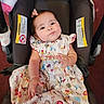baby, child, car_seat, dress, patterned_clothing, animal_print, plush_toy, unicorn, infant, cute, bow, sitting, indoors, person, face, hand, foot, happy, car_seat_warning_label, colorful