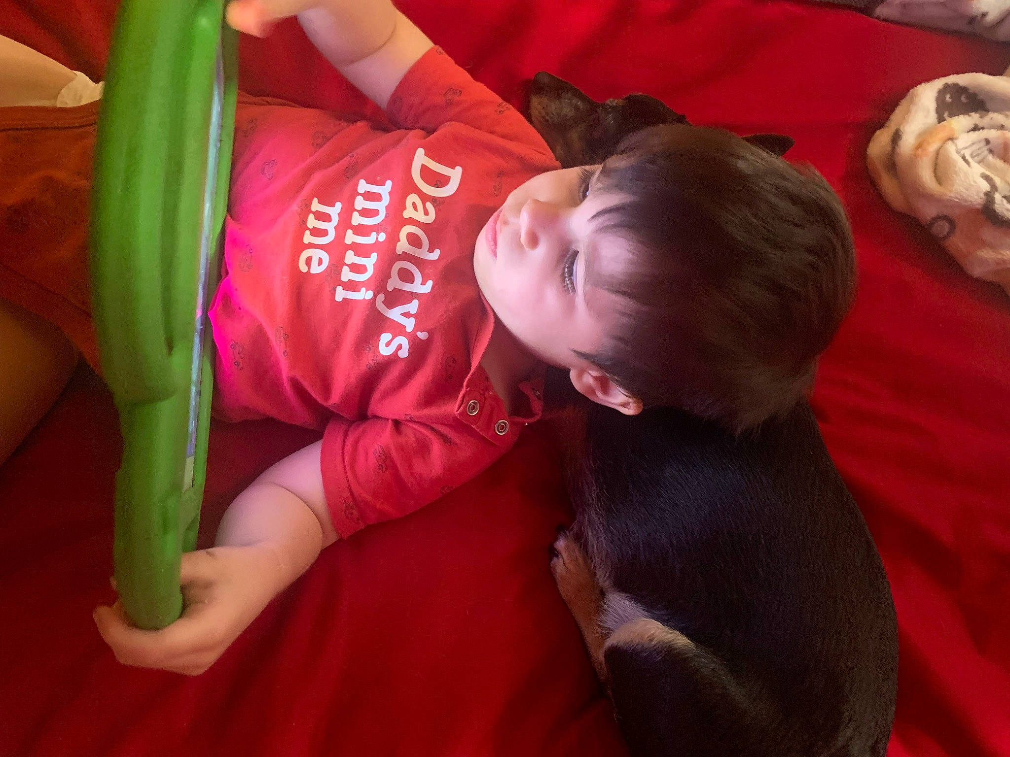 Sebastian is registered to the contest to win money with this photo: baby, baby_toddler_clothing, child, comfort, elbow, flooring, fun, happy, human_leg, linens, magenta, person, room, sitting, sleeve, t_shirt, toddler