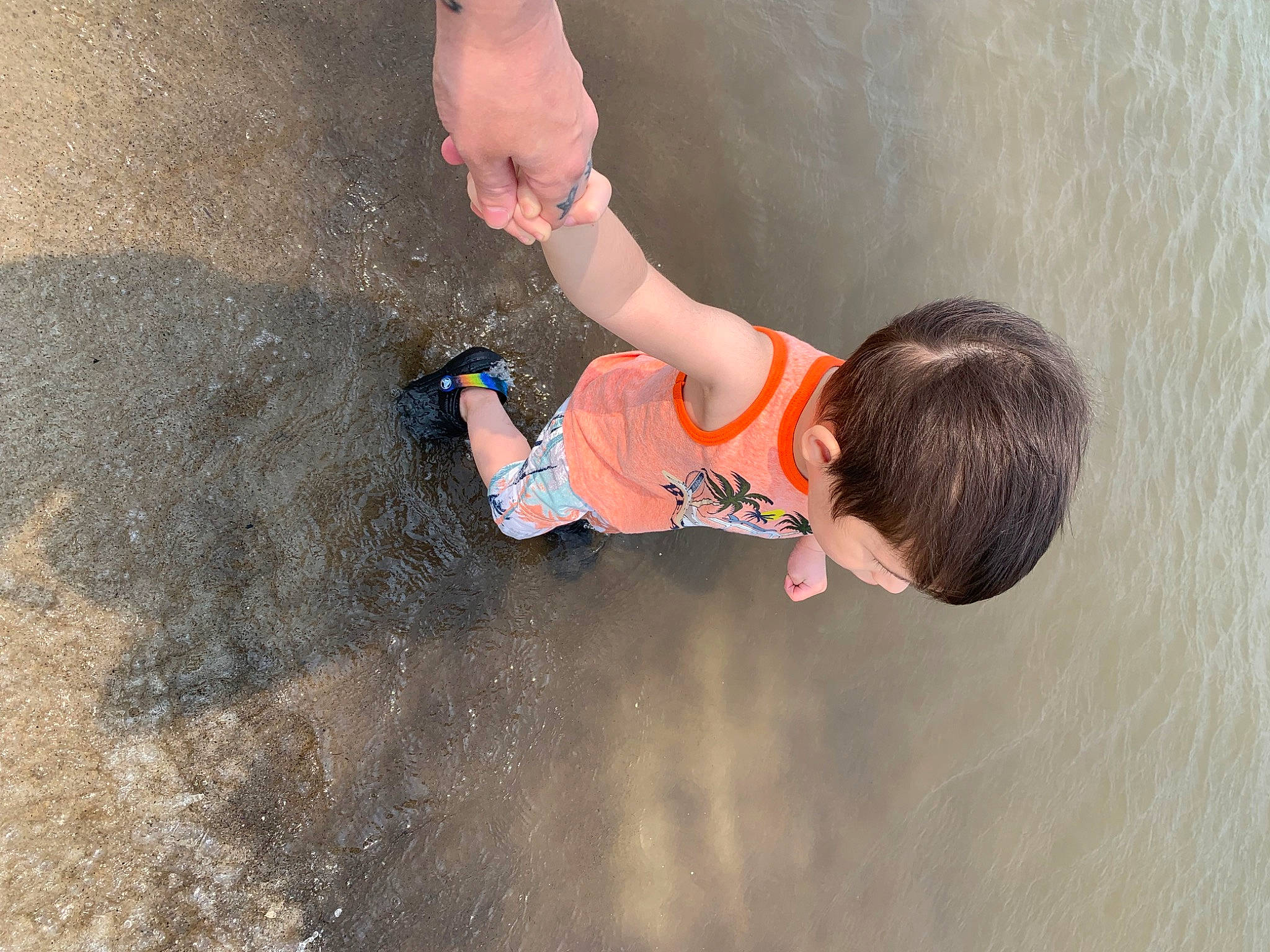 Sebastian is registered to the contest to win money with this photo: adventure, asphalt, baby, beach, child, concrete, elbow, fun, gesture, human_leg, leisure, person, play, puddle, recreation, sand, soil, t_shirt, toddler, water