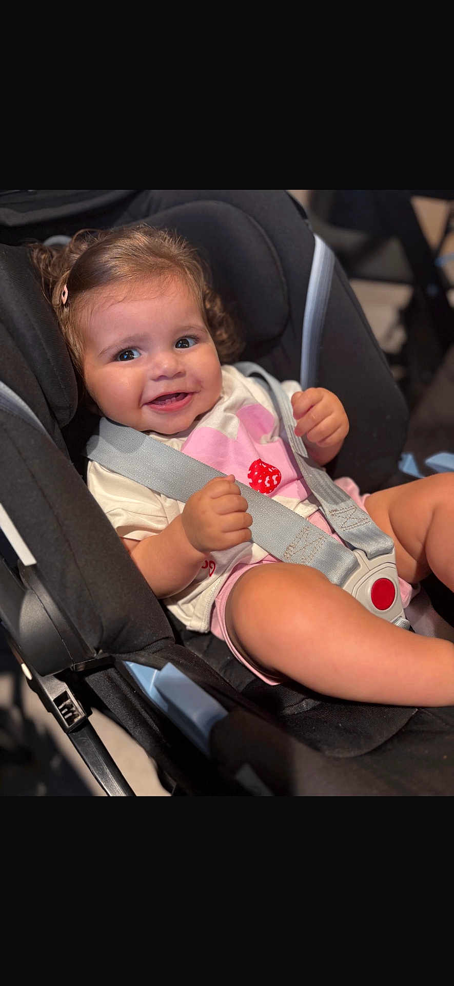 Nour is registered to the contest to win money with this photo: toddler, child, car_seat, harness, smile, curly_hair, pink_clip, baby, seatbelt, happy, cute, indoor, person, infant, clothing, sitting, safety, cheeks, portrait, closeup