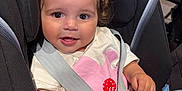 Nour participe au concours pour gagner de l'argent avec cette photo : baby, child, car_seat, safety_harness, smiling, curly_hair, pink_shorts, white_shirt, indoor, seatbelt, cute, happy, infant, person, portrait, secure, young_child, bright, close_up, adorable