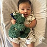 Ayden joined the competition — help win amazing prizes! baby, infant, toy, plush, dinosaur, blanket, clothing, romper, sneakers, smile, face, hand, footwear, cute, lying_down, soft_texture, child, portrait, indoor, playful