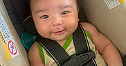 Ayden is registered to the contest to win money with this photo: baby, car_seat, child, smile, face, straps, clothing, infant, seatbelt, cute, person, indoors, sitting, hair, skin, hand, shoulder, warning_label, pacifier, secure