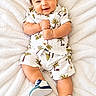 Ayden joined the competition — help win amazing prizes! baby, child, infant, smiling, happy, portrait, lying_down, blanket, white_blanket, floral_clothing, tropical_print, palm_trees, sneakers, shoes, indoors, cozy, face, short_hair, fashion, photography