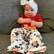 Ava joined the competition — help win amazing prizes! baby, child, smile, headband, red_shirt, cow_print_pants, barefoot, couch, gray_couch, seated, happy, cute, indoors, infant, clothing, person, portrait, hands, feet, home