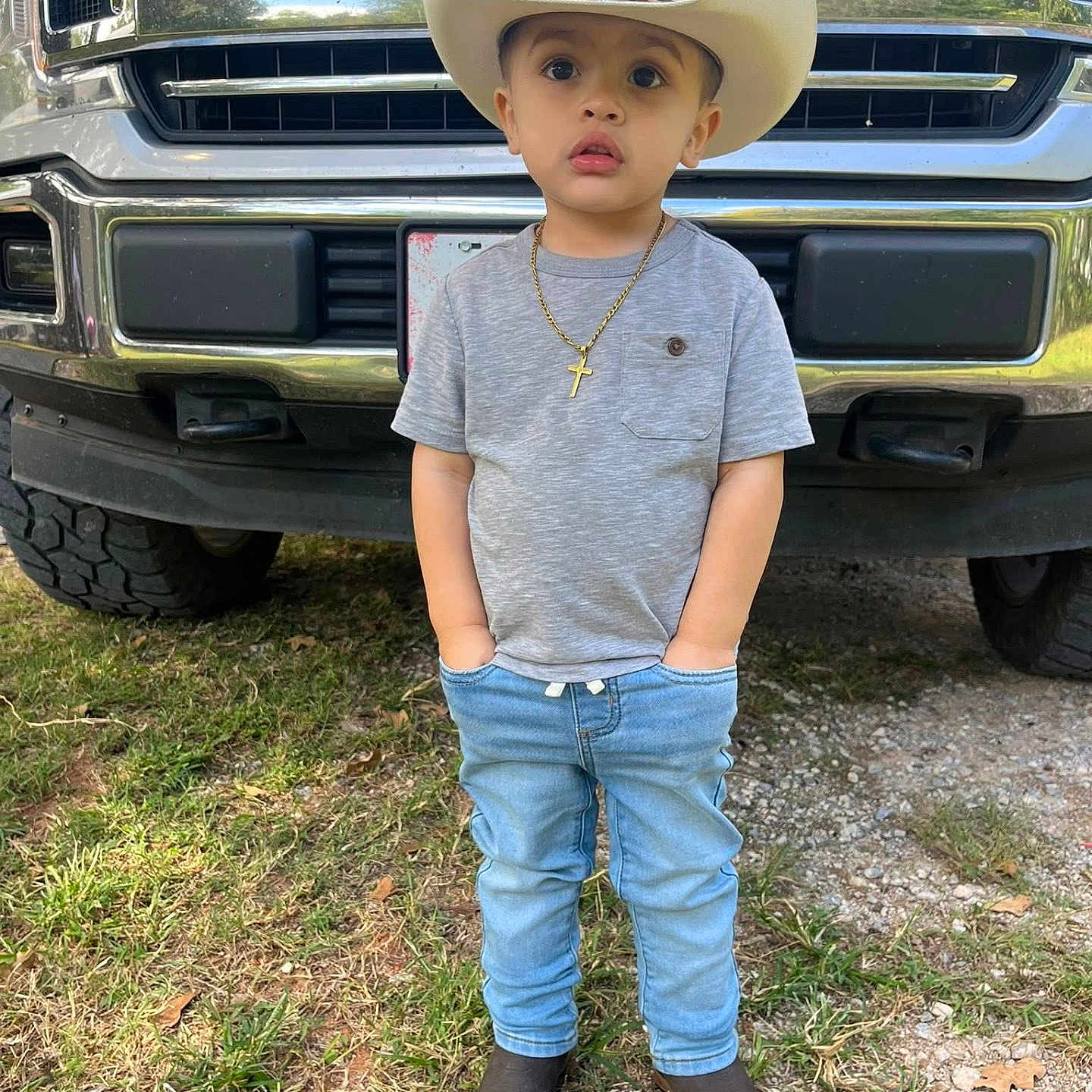Abel joined the competition — help win amazing prizes! child, boy, cowboy_hat, jeans, tshirt, boots, necklace, cross, truck, ford, outdoor, grass, dirt, vehicle, portrait, standing, casual_clothing, young_child, hands_in_pockets, daytime