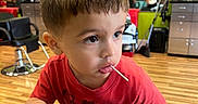Abel is registered to the contest to win money with this photo: boy, cabinet, chair, child, curious, floor, furniture, haircut, hand, indoor, lollipop, mirror, person, red_shirt, reflection, salon, television, toddler, toy_car, wood_floor