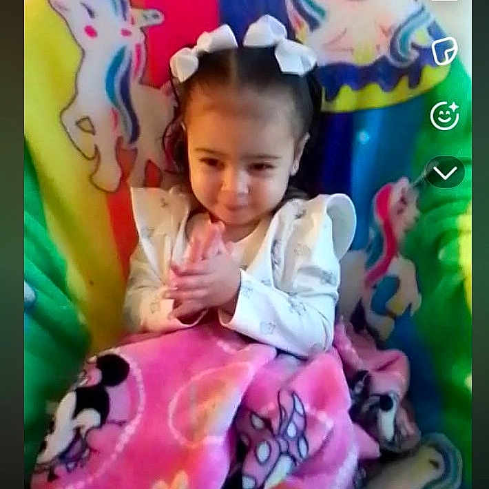 Kaia is registered to the contest to win money with this photo: child, girl, bows, blanket, pink_blanket, unicorn, colorful_background, sitting, smiling, clothing, indoor, cute, young_child, portrait, happy, wrapped, hands, hair, playful, childhood