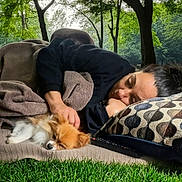 Bella is registered to the contest to win money with this photo: blanket, casual_clothing, companion, cozy, cushion, daylight, dog, fur, grass, nature, outdoor, peaceful, pet, pillow, relaxation, resting, sleeping, small_dog, tree, woman