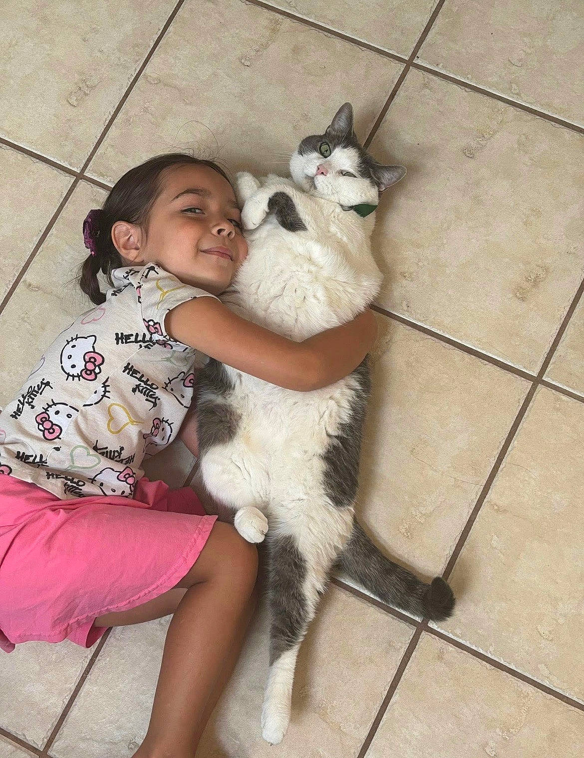 Pepper is registered to the contest to win money with this photo: affection, casual_clothing, cat, child, cute, floor, fur, happy, hello_kitty, hugging, indoor, pet, playful, relaxed, shirt, shorts, smiling, tail, tile, whiskers