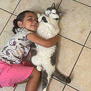 Pepper is registered to the contest to win money with this photo: child, cat, hugging, floor, tile, happy, pet, indoor, casual_clothing, shorts, shirt, hello_kitty, cute, relaxed, affection, smiling, fur, whiskers, tail, playful