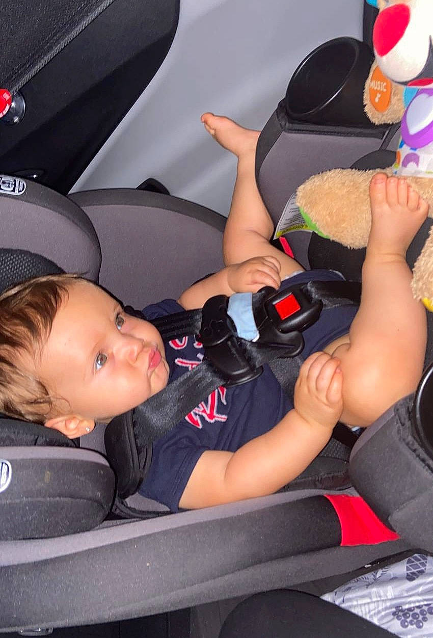 Zander is registered to the contest to win money with this photo: auto_part, automotive_design, baby, car_seat, child, comfort, finger, fun, hand, hat, human_leg, lap, leisure, motor_vehicle, person, product, shorts, sitting, thigh, toddler