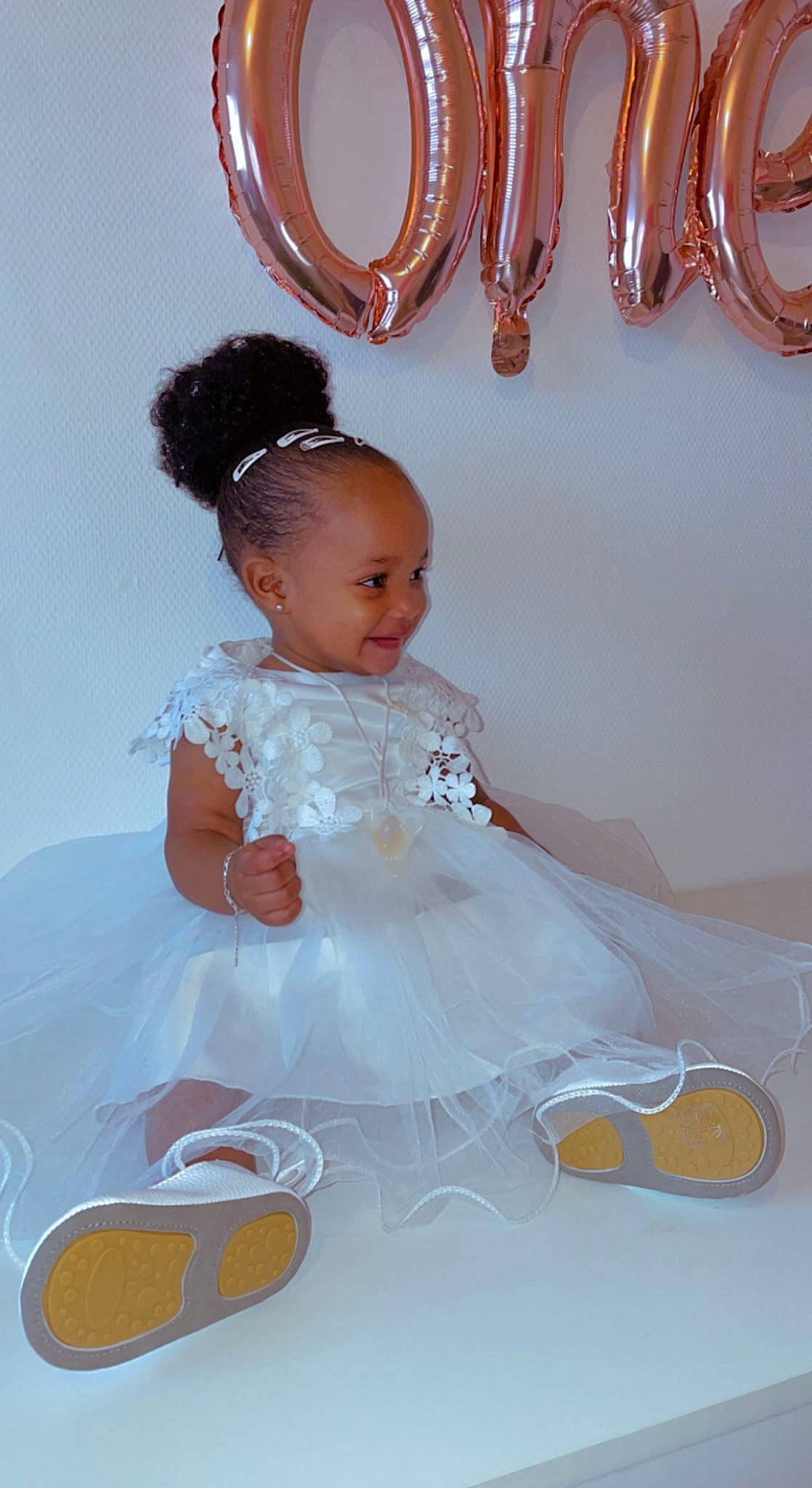 Mbalia a rejoint le concours — aidez-le/la à gagner de superbes lots ! baby, baby_toddler_clothing, bridal_accessory, dress, embellishment, event, fashion_accessory, formal_wear, gown, hairstyle, happy, headpiece, jewellery, joy, peach, person, pink, sitting, textile, toddler