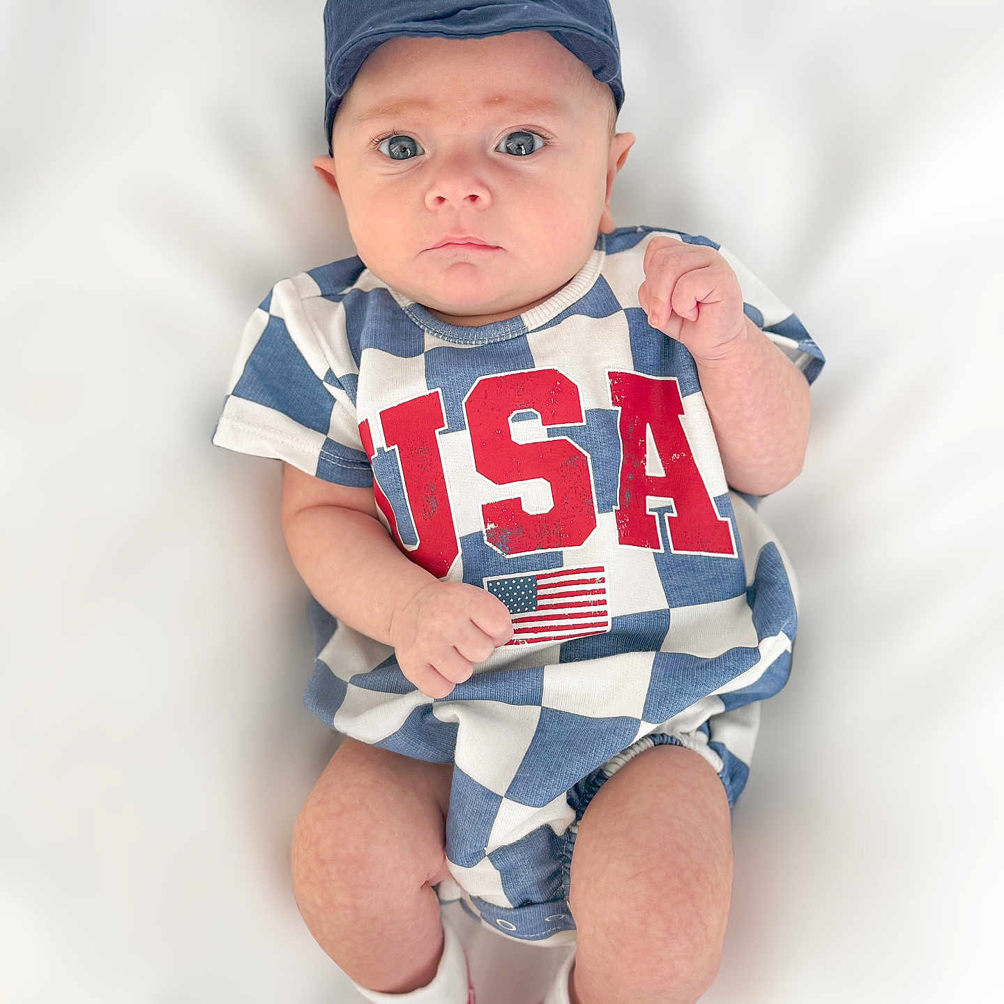 Jackson is registered to the contest to win money with this photo: baby, baseballcap, bodypart, cap, clothing, face, finger, footwear, hand, hat, head, hosiery, person, photography, portrait, shirt, shoe, shorts, sitting, sock