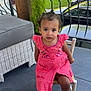 Kezia a rejoint le concours — aidez-le/la à gagner de superbes lots ! toddler, child, pink_dress, barefoot, chair, porch, outdoor, greenery, furniture, wicker, curly_hair, expression, garden, railing, car, daylight, casual, sitting, looking_up, cute