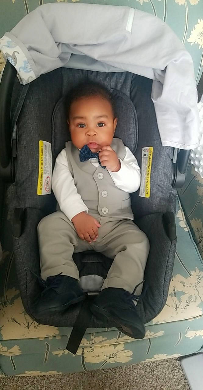 Cayden is registered to the contest to win money with this photo: baby, baby_carriage, baby_products, baby_toddler_clothing, bag, boot, car_seat, chair, cheek, child, comfort, fun, outerwear, people, person, sitting, sneakers, thumb, toddler, uniform