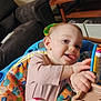 activity_chair, baby, child, clothing, colorful, couch, furniture, hand, happy, indoor, infant, living_room, person, playful, seat, smiling, storage_bins, tongue_out, toy, wooden_shelf