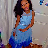 Reya is registered to the contest to win money with this photo: child, girl, blue_dress, smile, indoor, wood_floor, door, phone, bracelet, hair, stitch_sticker, happy, posing, fashion, flooring, wall, accessory, portrait, person, footwear