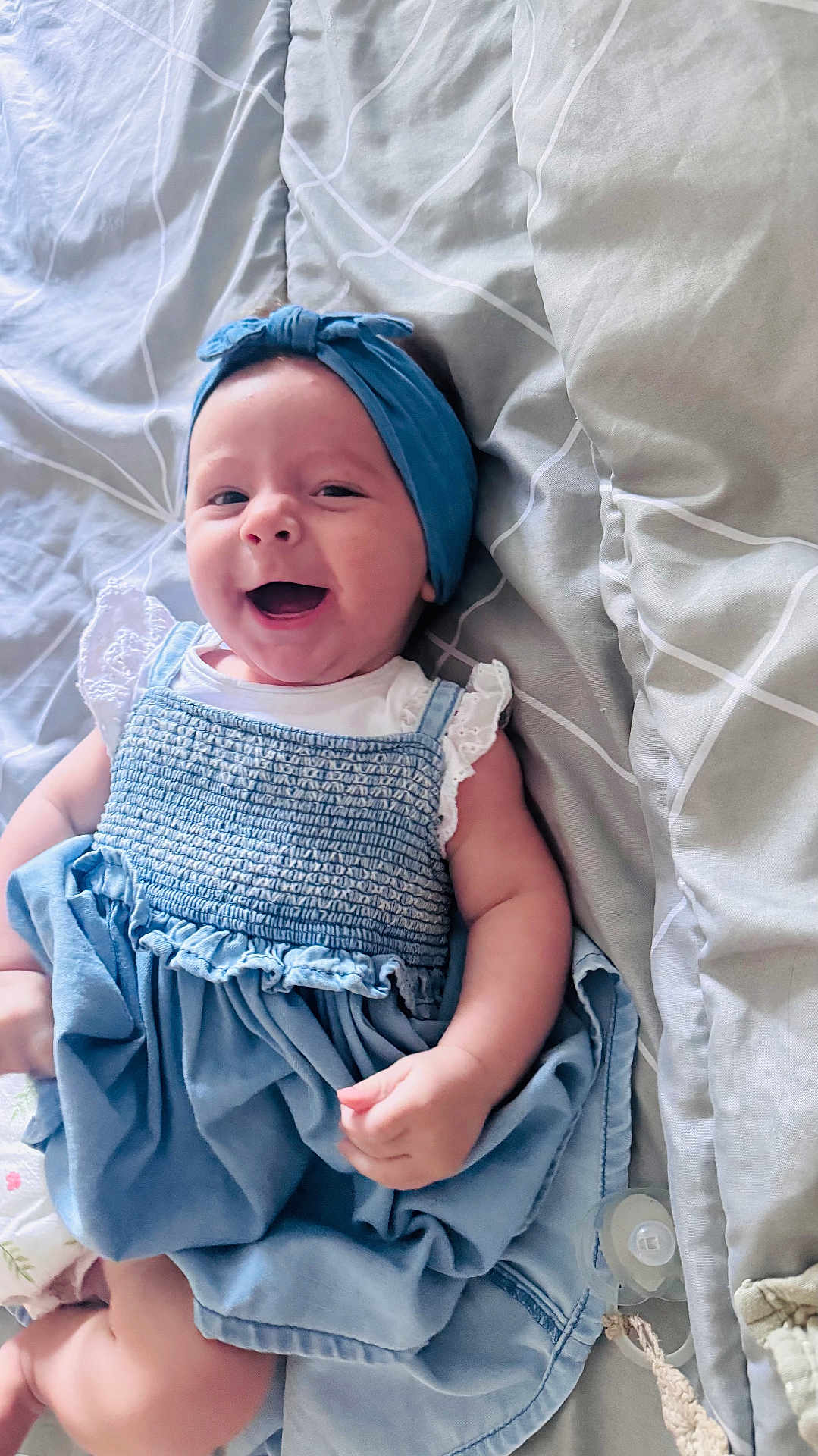 Lùna a rejoint le concours — aidez-le/la à gagner de superbes lots ! baby, smiling, blue_headband, blue_dress, bedspread, lying_down, infant, happy, cute, child, indoors, fabric, person, skin, hand, face, head, clothing, pacifier, soft_texture